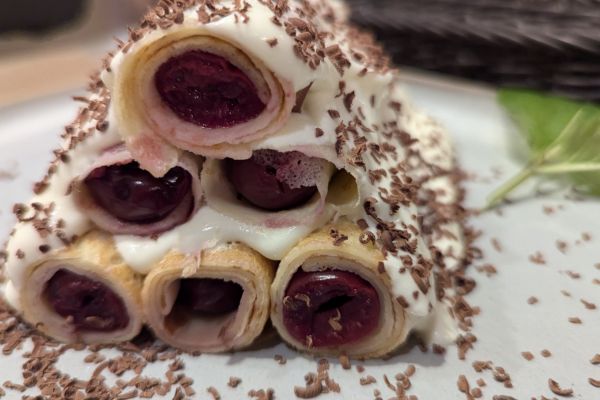 Moldovan crepes cake filled with cherries and topped with chocolate