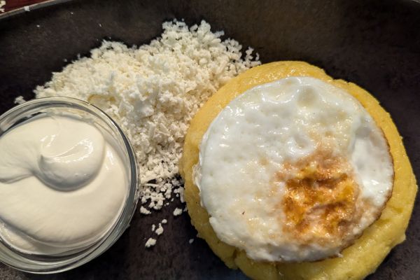Golden Moldovan mămăligă with sour cream and cheese on a plate
