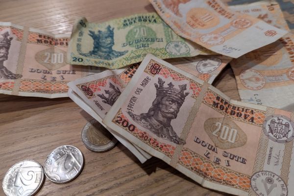 Moldovan leu banknotes in different denominations spread out on a table and some lei coins