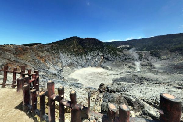 Volcanic crater at Tangkuban Perahu with rocky terrain, steaming vents, and a fenced lookout point.
