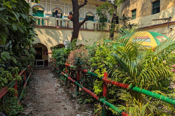 Leafy green cortyard and yellow building of Beauty Boarding in Dhaka